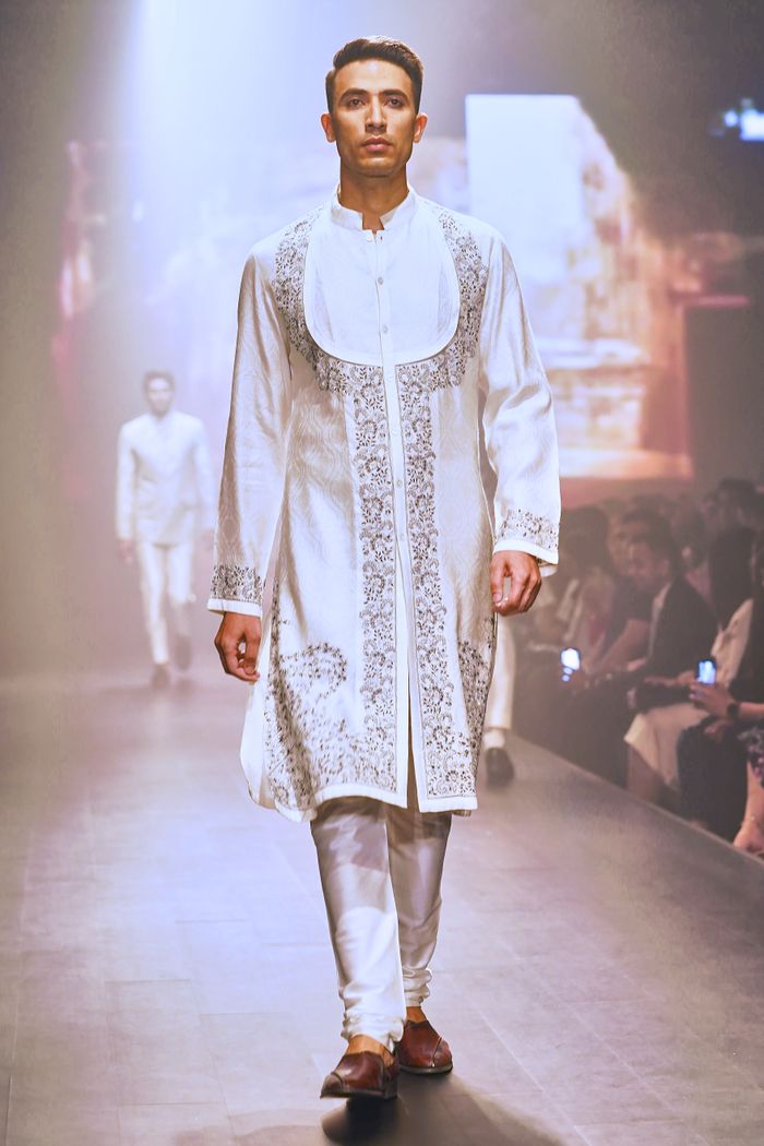 Model walking in traditional Indian attire during a fashion show.