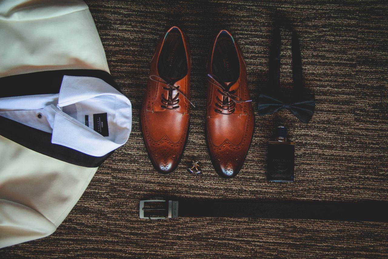 Flat lay of men's fashion accessories including shoes, bow tie, and jacket for a formal event.
