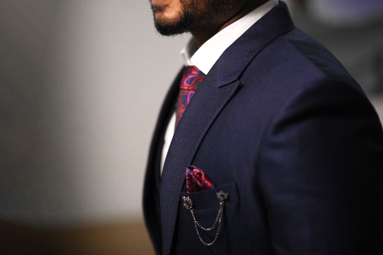 Close-up of a man in a navy suit with a stylish red tie and pocket square.