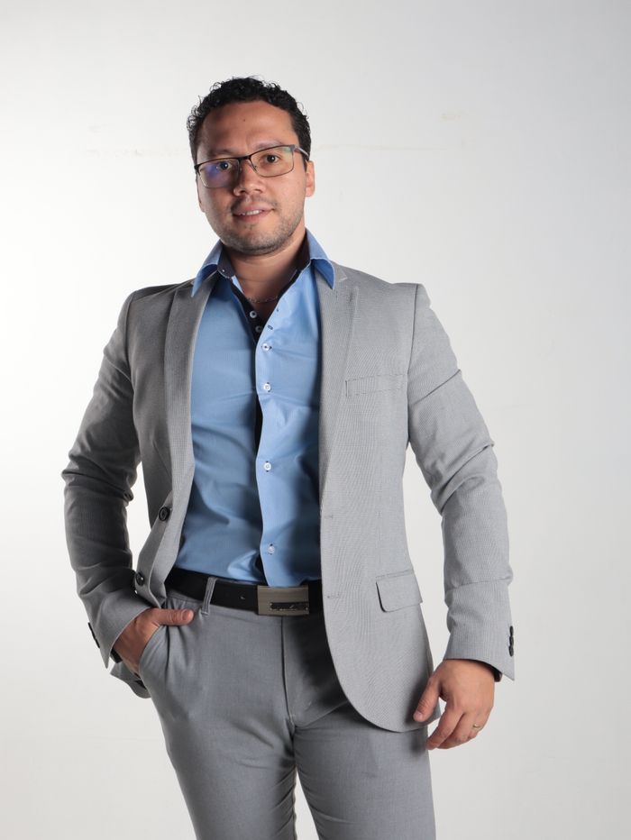Confident man in grey suit and blue shirt poses for a professional portrait.